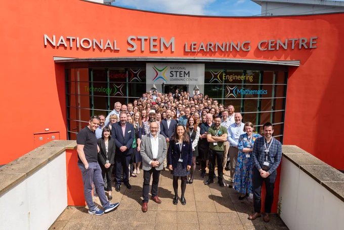 All staff stood outside National STEM Learning Centre, on a sunny day, happy and smiling.