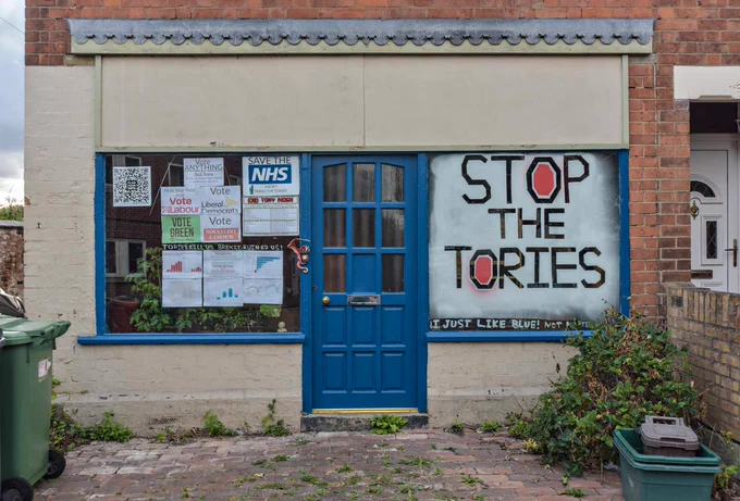 House window with postsers and a sign saying 'Stop The Tories' in Gloucester July 2024