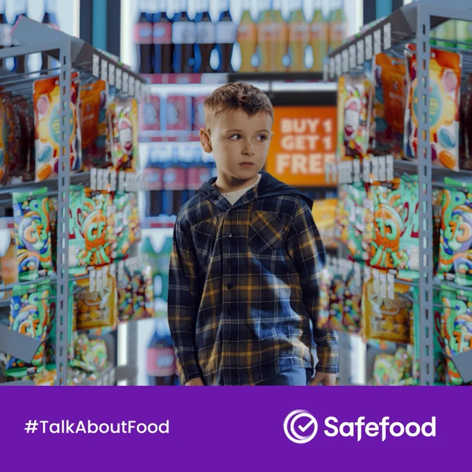 A boy standing in a shop. The text in the image says #TalkAboutFood. The Safe Food logo is in the image. 