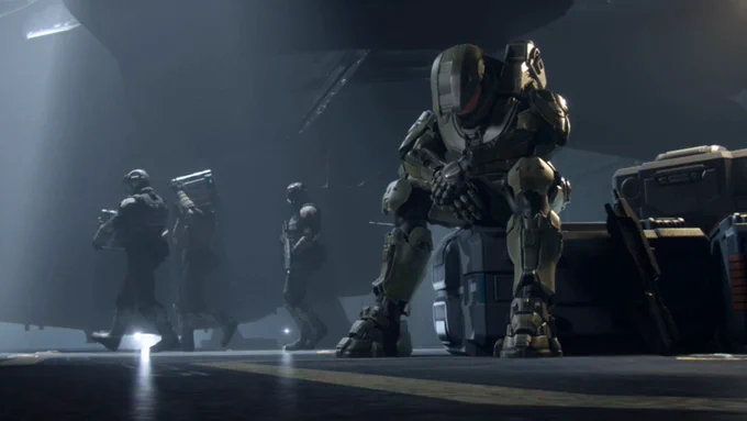 Halo 4 screenshot of the Master Chief sat looking dejected on a crate as Marines pass by