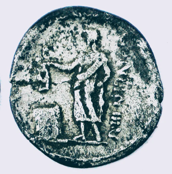 Circular silver coin, very worn, showing man standing facing left reaching out to drop a card marked V into a box