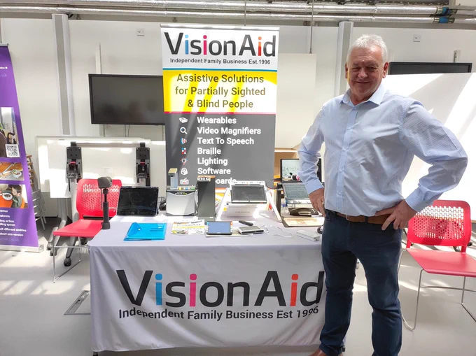 Sales colleague, Dave, stood smiling at the camera in front of the VisionAid stand.