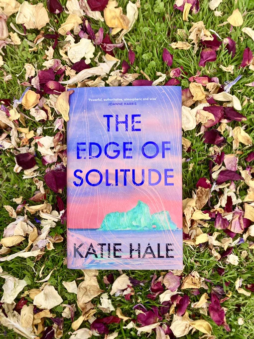 Photo shows a copy of #TheEdgeOfSolitude lying on the grass, surrounded by petals.