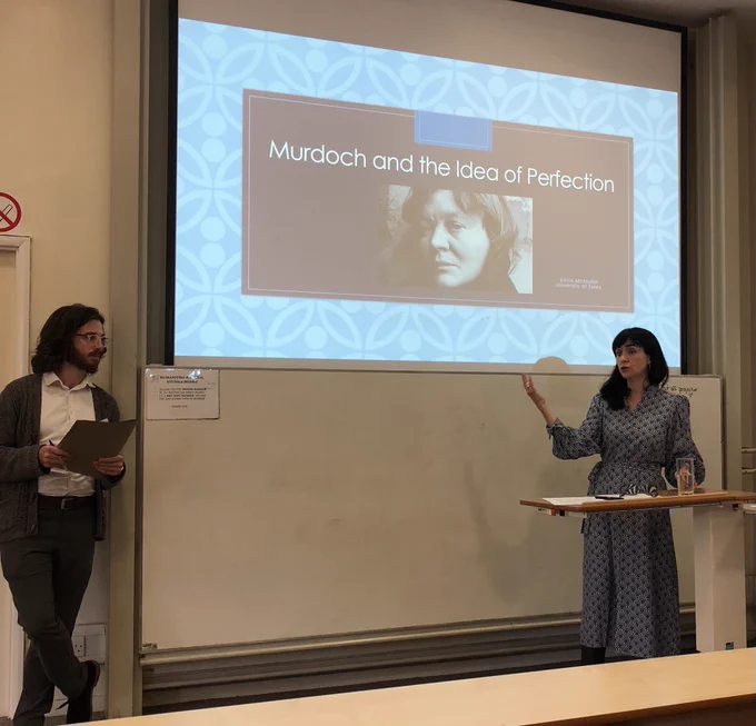 Photo of McMullin answering a question in front of a slide depicting Iris Murdoch and giving the title of the talk.