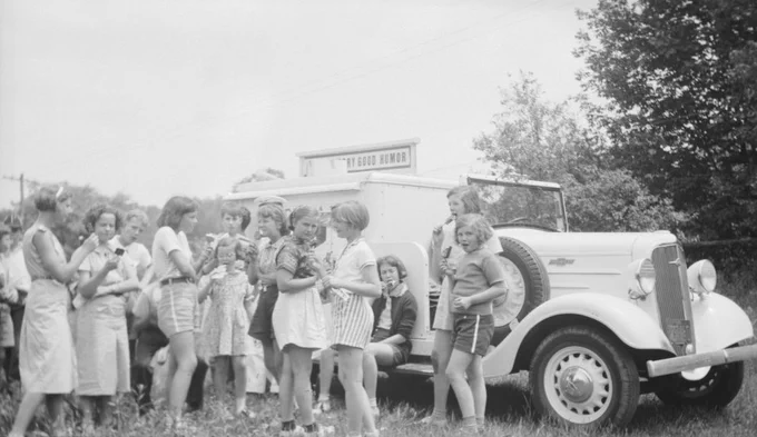 Black and white photo of girls gathered by an ice cream truck holding ice cream cones