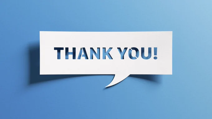 A white piece of card lies on a light blue background. The white card is in the shape of a rectangular speech bubble and has letters cut out from its middle. The card reads, 'Thank you!'