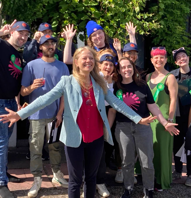Sian Berry smiling among a group of Green New Deal rising volunteers wearing pink sunrise logos on their t-shirts.