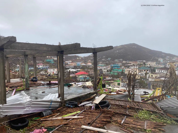 Concrete frame of damaged building, with destroyed buildings in community in the background, on Union Island SVG