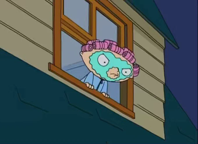 Angry Stewie in curlers and expensive skincare mask looks angrily out the window of his Caucasian home