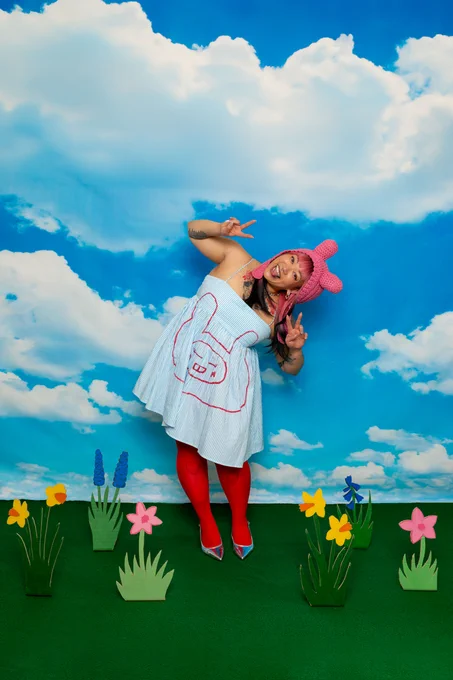 Woman wearing a white dress, dancing in front of a blue sky background