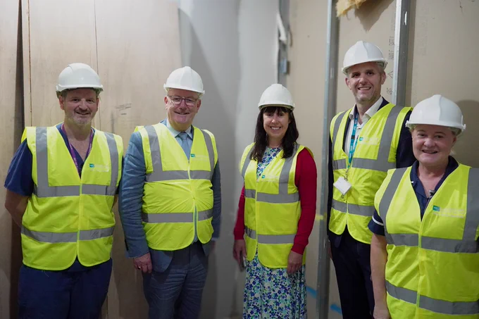 A photo of five people wearing high visibility vests and hard hats at the construction site for the urgent care centre at Ulster Hospital. From left to right, the people are: Emergency Department Consultant, Dr Andrew Dobbin, Health Minister Mike Nesbitt, Roisin Coulter, Chief Executive of South Eastern Trust,  Jonathan Bradshaw, Assistant Director of Estates South Eastern Trust and  Jenny Nicholson, Lead Nurse, Emergency Department
