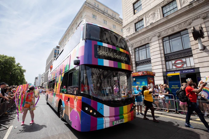 The Transport UK London Bus Pride Bus travels along the Pride in London Parade route past Green Park station
