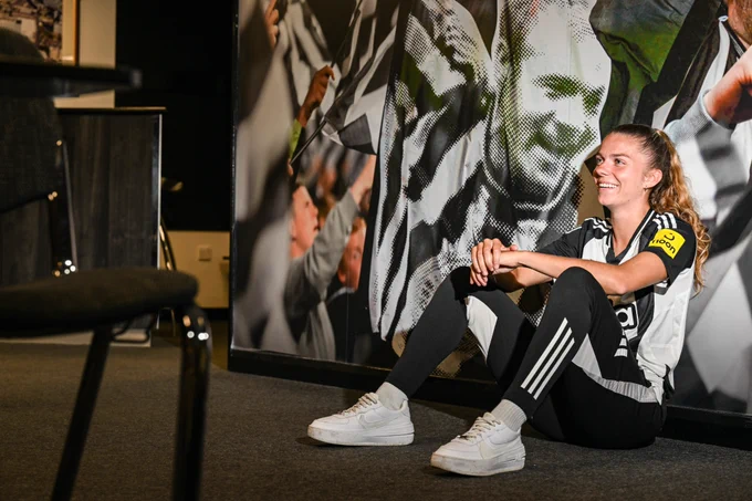 Andrews smiles as she's photo'd in front of an Alan Shearer graphic at SJP.