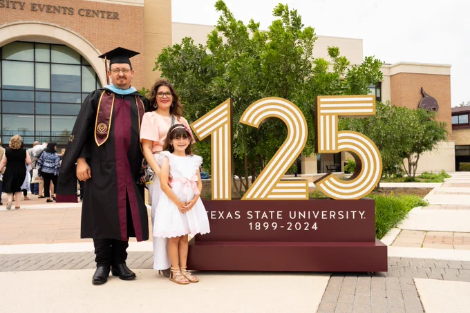 Family at TXST graduation in front of the TXST 125 sculpture