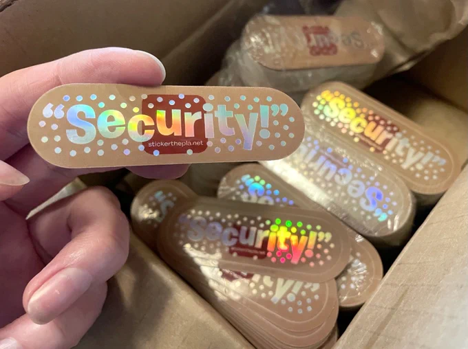 holographic sticker in the shape and appearance of a band-aid, that says "Security!"
