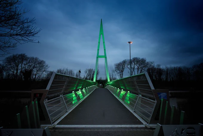Greystone footbridge lit green