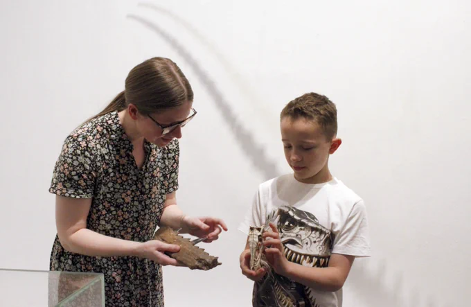 A photo showing two people holding objects in the exhibition Dinosaurs on the Doorstep.