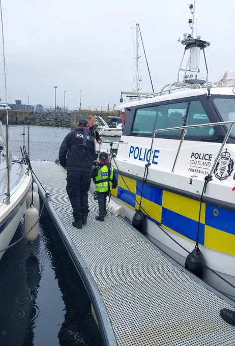 Young person with officers looking at police boat