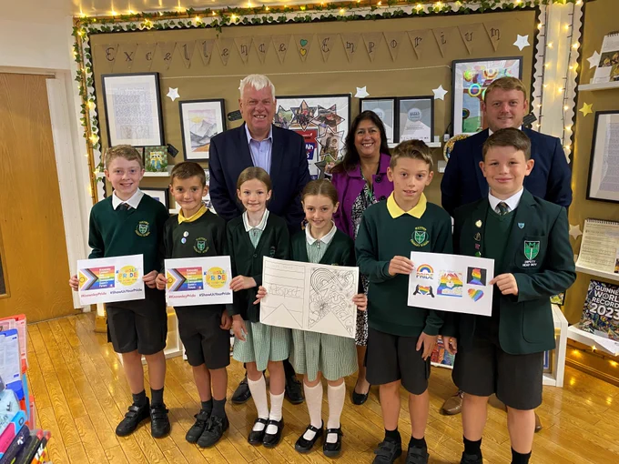 Leader of Knowsley Council, Cllr Graham Morgan and Carla Simkin from the Council's Culture and events team with Head teacher Tony James and pupils from Malvern Primary showing their flag designs