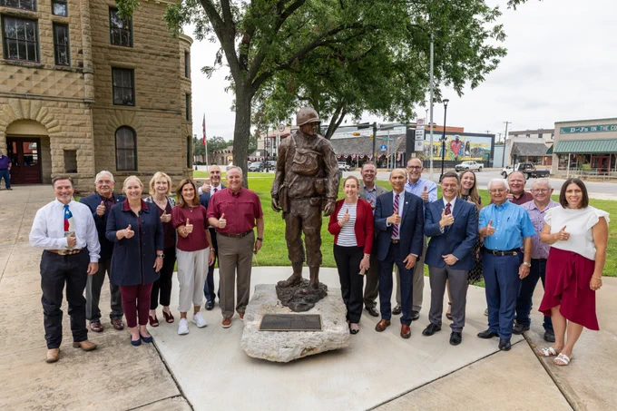 Leaders from Texas A&M and Mason and McCulloch County pose together by the James Earl Rudder statue in Brady, Texas.