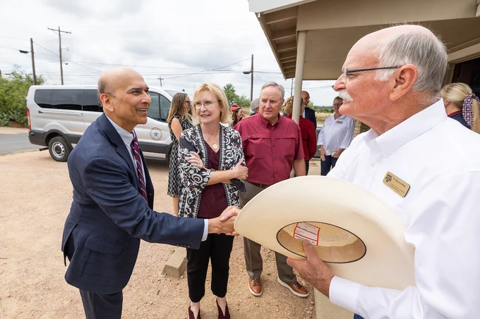 Dr. Indra Reddy of Texas A&M Health shakes hands with Dr. Glennon Mays from the Texas A&M veterinary medicine school. Susan Ballabina  and Texas A&M President Welsh stand nearby.