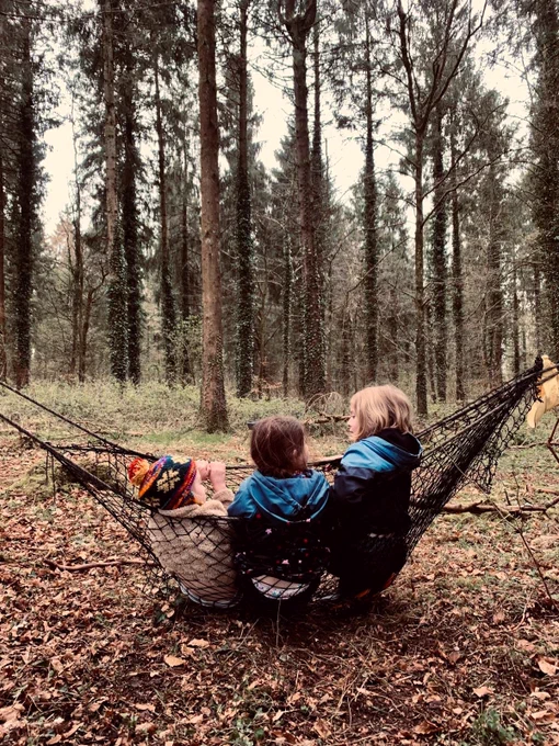 Two children in a hammock in a wooded area. Photo by Maverick Mums UK