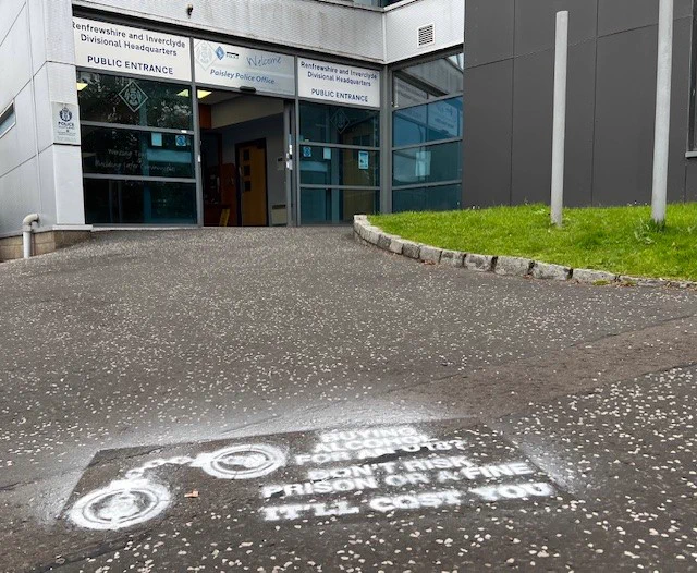 Main entrance of Paisley Police Station with the campaign information spray painted on the ground
