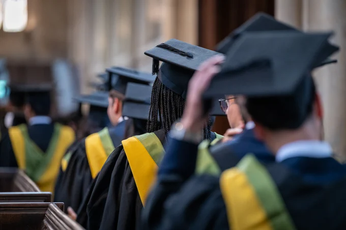 This is a picture of our students from the back. They are wearing their academic attire and are lined up to graduate.