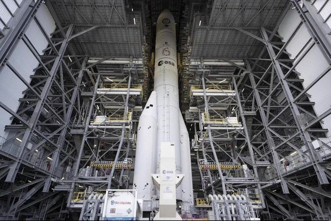 White rocket stands in a building with multiple layers of metal scaffolding.
