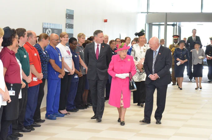 Queen Elizabeth II walks into Royal Papworth Hospital, the entrance to which is lined by Royal Papworth staff in their uniforms.
