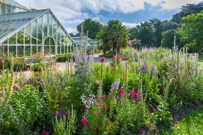 The glasshouse and surrounding flower beds abloom with flowers at the Cambridge University Botanic Garden.