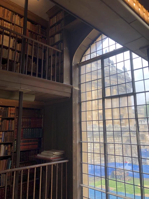A view of the Radcliffe Camera through a window from the All Souls College Library Office. To the left of the image, there are two floors of bookshelves.
