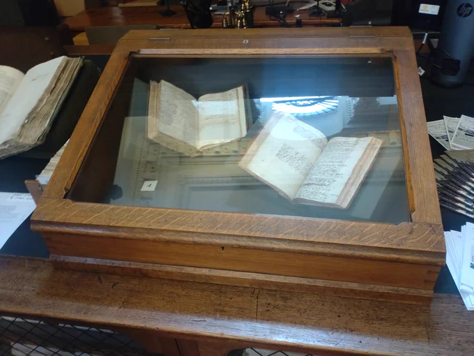 A wooden, glass-topped display case. Inside the case, there is a 17th century amalgamated manuscript of papers opened to show an alphabetical index and a 1631 catalogue compiled by Humphrey Dyson. 