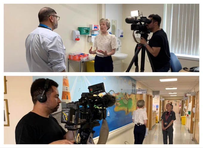 Two scenes depicting a video production in a hospital setting. In the top image, Dr Shaz Wahid is interviewed by journalist Helen Ford. She is holding a microphone, with camera operator Daniel filming the interaction. In the background are medical supplies and hospital room. The bottom image shows Daniel filming Laura on a ward corridor decorated with a colourful mural as she is interviewed by Helen.
