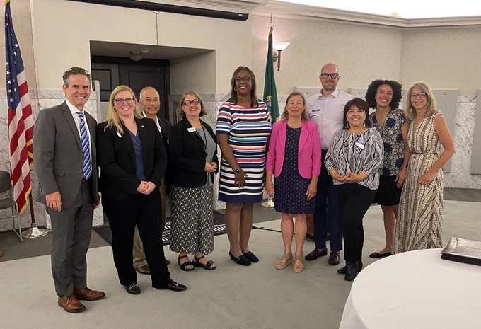 Participants and attendees at Washington payer coalition MOU signing stand in a group smiling. 