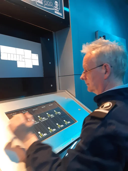 Me in a space navy jumpsuit looking intently at a console display with sliders.