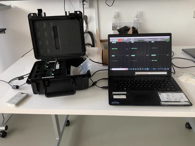 This is a picture of a table with a laptop with raw EMG data on it and the EMG machine.