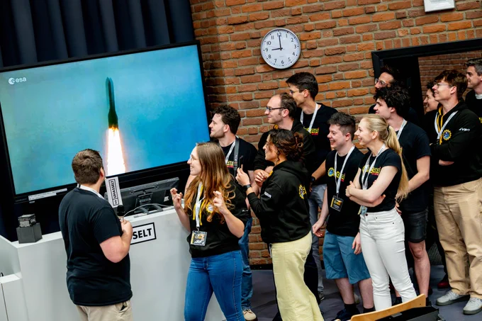 Studententeam OSCAR kijkt vol spanning naar de lancering van de raket op een groot scherm. 