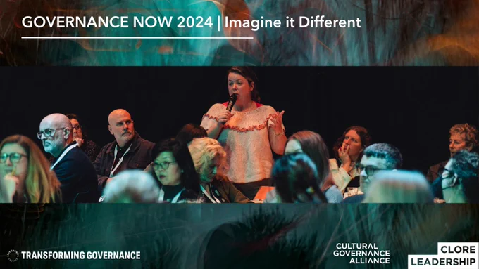 Governance Now 2024 Banner, white text on an abstract green background. TEXT: GOVERNANCE NOW 2024, Imagine it Different. IMAGE: A woman in a peach frilly jumper is stood up in a seated audience answering a question with a handheld microphone.