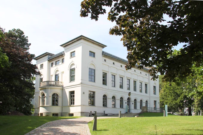 Das Gebäude "Villa von Bülow" gerahmt von Bäumen im Sommer.