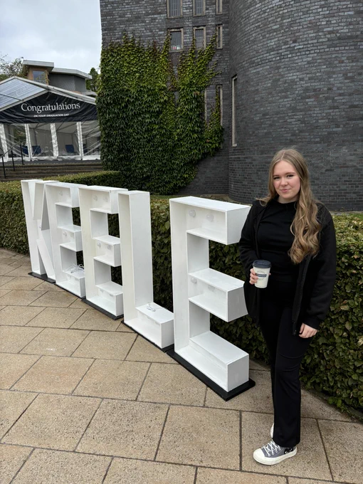 Newcastle College student Loren stood in front of giant letters that spell the word Keele
