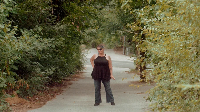 Photo of Linda Tirado standing on a pathway with trees surrounding it.