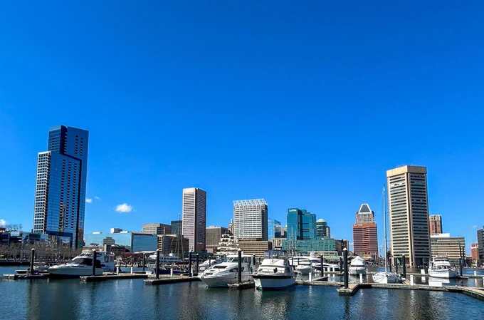 View of Baltimore's Inner Harbor featuring docked boats and skyscrapers under a clear blue sky.