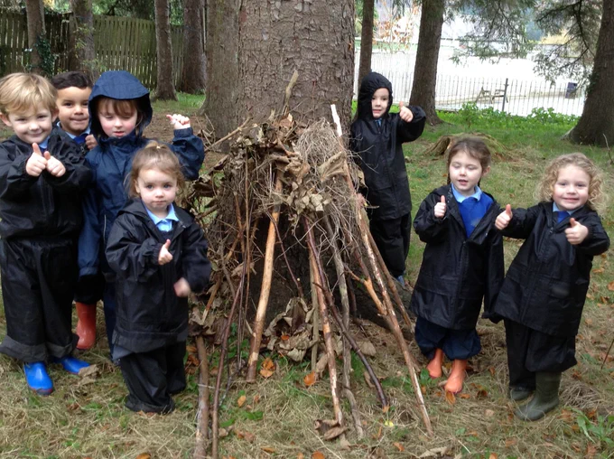 Children outside in nature building a den from wood and twigs.