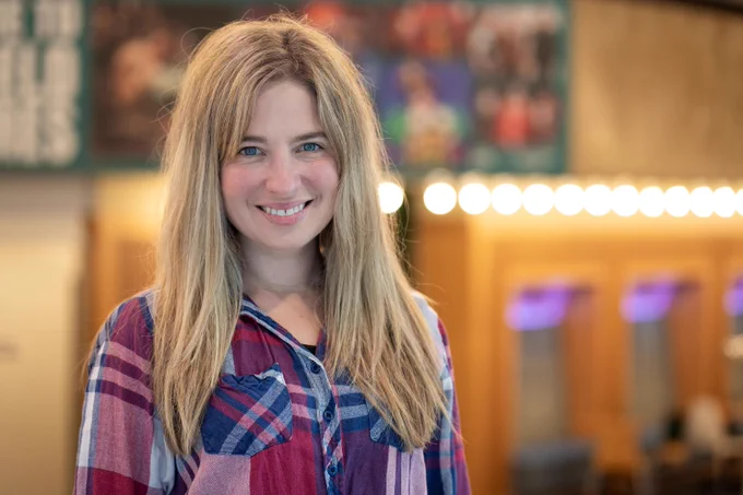 A woman wearing a red and blue shirt stands in the foyer of the Crucible Theatre.