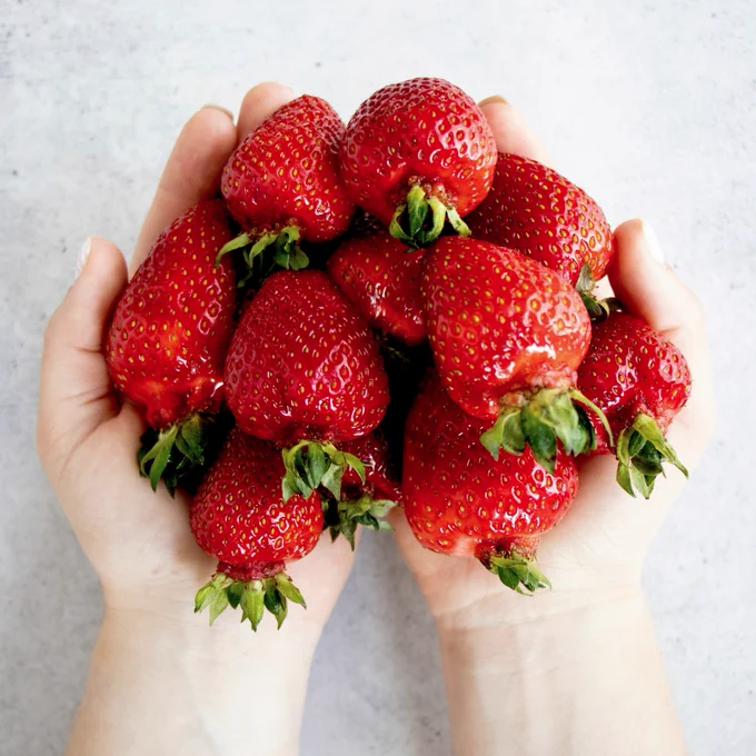 Two hands filled with strawberries. 