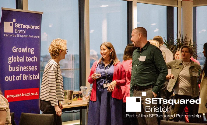 A group of people networking at Enterprising Women Showcase. SETsquared Bristol logo. Banner with text: Growing global tech businesses out of Bristol