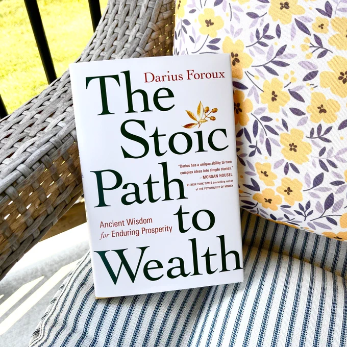 THE STOIC PATH TO WEALTH book on a wicker chair with striped and floral cushions