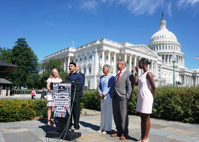 Foster youth expert speaking at a podium in front of the Capitol wearing a blue top and black pants. 