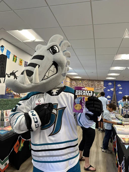 San Jose Barracuda’s Frenzy pointing to a book at a book fair called “Hockey’s Greatest Myths and Legends”